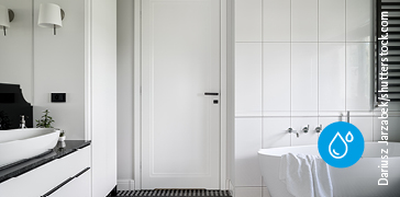 Weisse Tür in einem hellen Badezimmer mit Badewanne und Waschbecken.