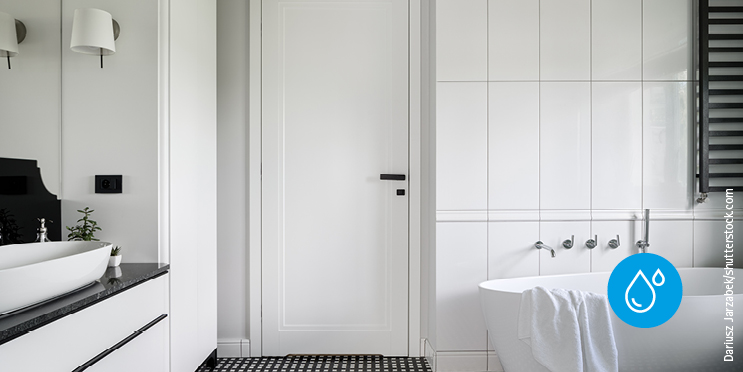 Weisse Tür in einem hellen Badezimmer mit Badewanne und Waschbecken.