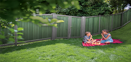 Sichtschutzzaun mit grünem Rasen und spielenden Kindern